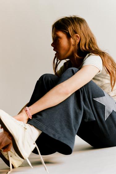 Брюки из мягкой ткани  с эффектом потертости и звездами- Заказать в России